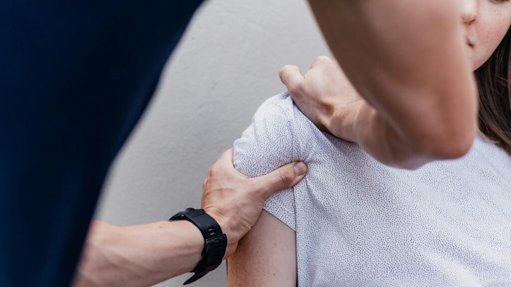 Fysiotherapeut onderzoekt schouder van een patiënt, passend bij keuze voor fysiotherapie of chiropractie