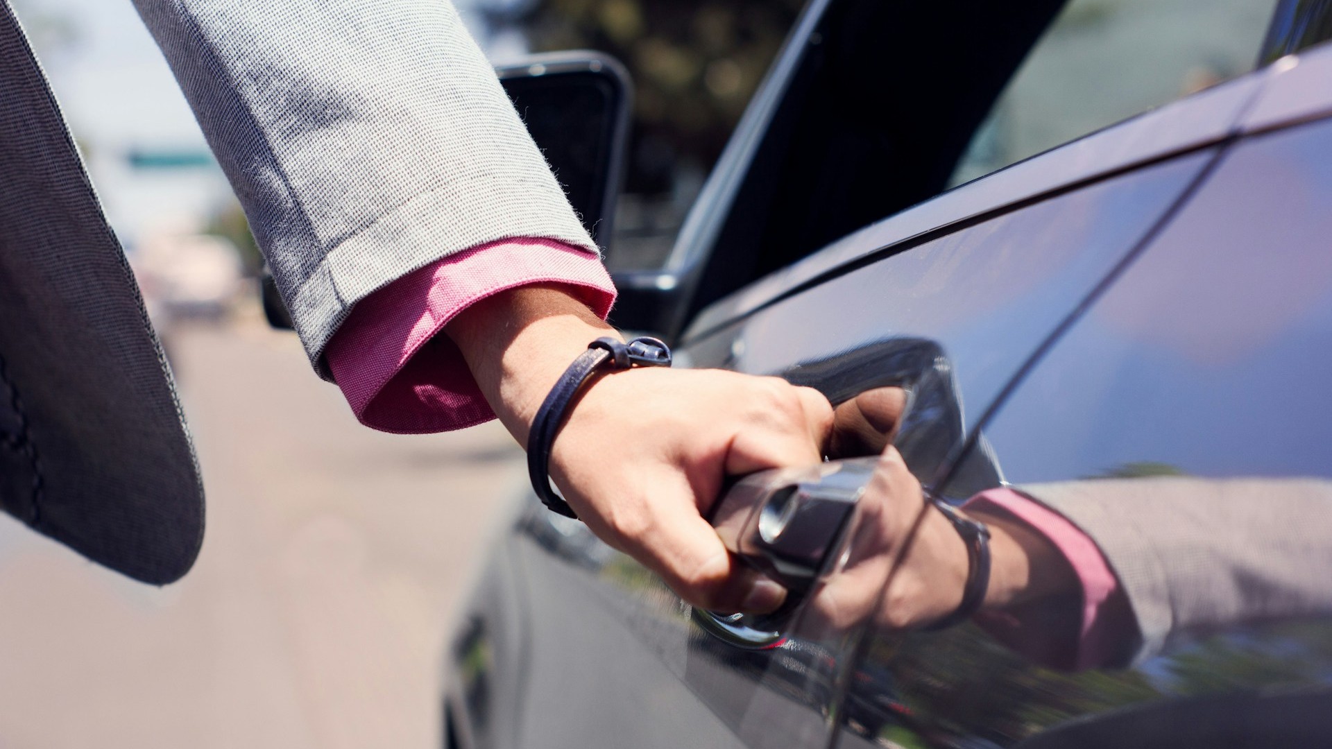 Hand opent autodeur met sleutel bij controle van startonderbreker en alarmsysteem