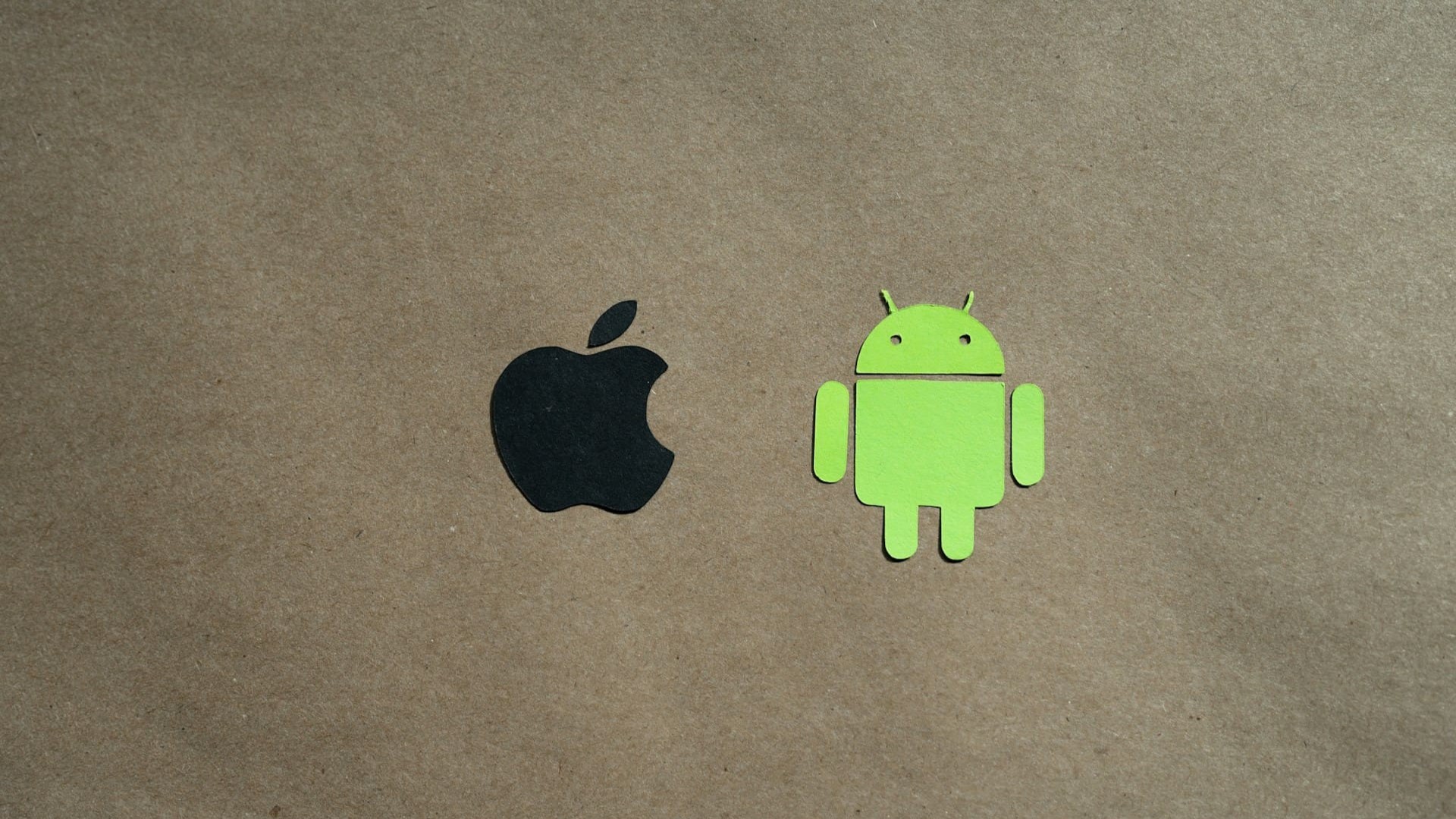 Android en iOS logo naast elkaar op kartonnen achtergrond als visuele vergelijking