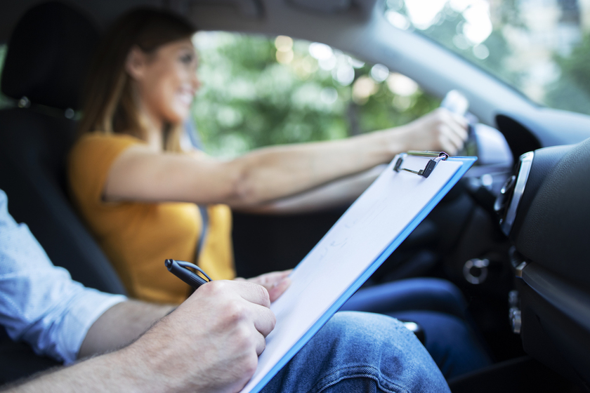 Rijinstructeur vult checklist in terwijl leerling autorijdt tijdens rijles.